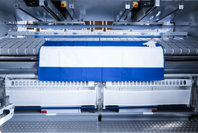 Manufacturer photograph of the blue Nomex wax cloth with a white silicone flap laid across an ironer